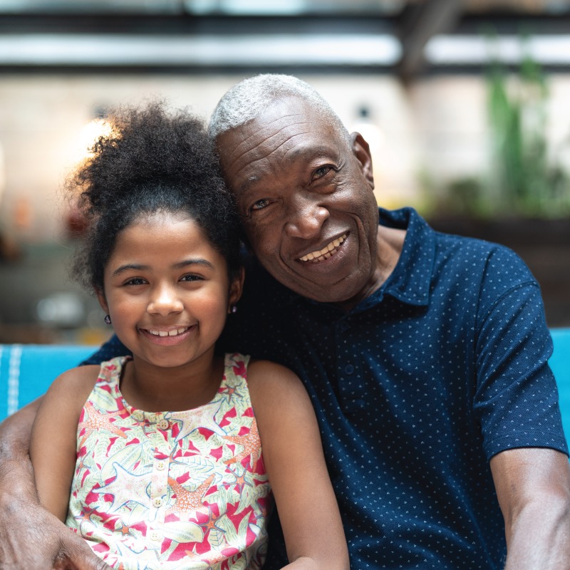 CC-Home-Inset-Photo Elderly black man sitting next to his great granddaughter and smiling.